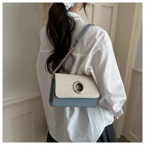 Vue rapprochée du sac à bandoulière en paille et cuir avec une élégante fermeture ronde dorée.