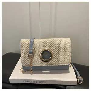 Vue détaillée d'un sac bandoulière élégant en paille tissée et cuir bleu avec anneau métal.
