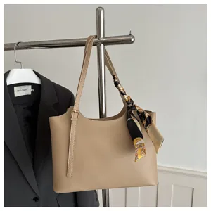 Vista dettagliata di una borsa a spalla beige in ecopelle con foulard fantasia.