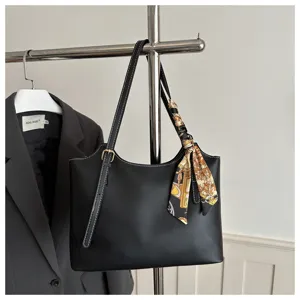 Primo piano della borsa tote nera in pelle con eleganti cuciture bianche e foulard di seta stampato.