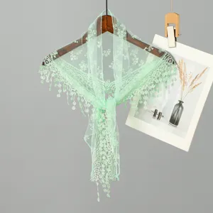 Gedetailleerd zicht op mintgroene kanten driehoekige sjaal aan een houten hanger