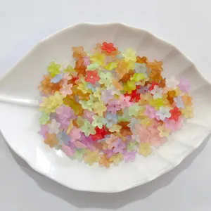Assorted colorful mini five-petal flower beads displayed on a white leaf-shaped ceramic plate.