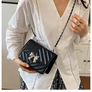 Fashionable black quilted crossbody bag with stylish silver bow and chain strap for women.