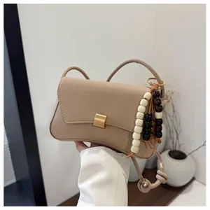 Vista dettagliata della borsa a tracolla beige alla moda con perline di legno e tracolla.