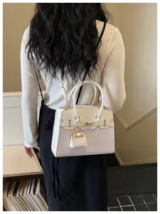 Chic two-tone shoulder bag with crocodile texture, metal lock, and top handle style.