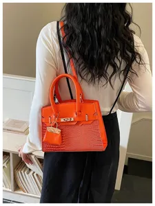 Orange crocodile texture handbag detailed view showing structured design and metal lock closure.