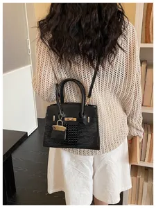 Detail view of black crocodile texture patchwork shoulder bag with golden lock hardware charm.