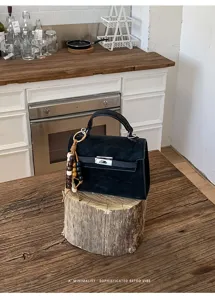 Sac à main rétro noir en suédine avec fermeture métallique et charm perlé élégant.