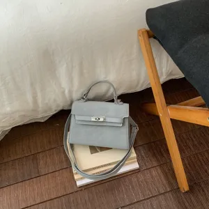 Sac à main gris élégant avec bandoulière et design de serrure, parfait pour la saison.