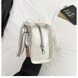 Detailansicht der glänzenden weißen minimalistischen Schultertasche mit Reißverschluss.