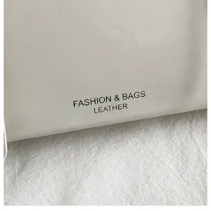 Nahaufnahme der minimalistischen weißen Leder-Umhängetasche mit feiner Textur und Print.