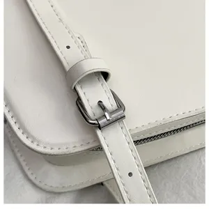 Weißer Umhängetasche Detailaufnahme mit verstellbarem Riemen, Metallschnalle und feiner Naht.
