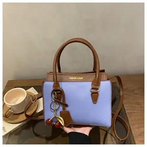 Stylish two-tone shoulder bag for women, featuring chic cherry charm, top handle and crossbody strap.