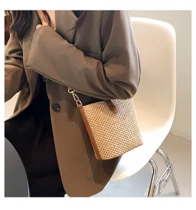 Chic summer straw woven bucket bag detail, stylish brown leather trim and metal chain strap.