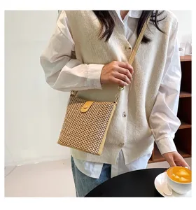 Detailed shot of a casual straw woven cross-body bag worn by a model in a cozy café setting.
