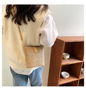 Detail view of the woven straw bucket bag worn crossbody, showing texture and design.