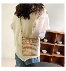 Detailed shot of a stylish woven straw crossbody bag worn by a model, showing texture and design.