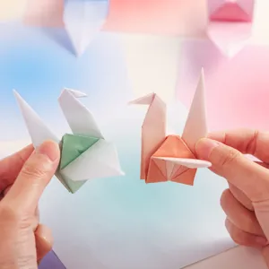 Detailaufnahme von handgefertigten Origami-Kranichen aus zartem Pastell-Farbverlauf-Papier.