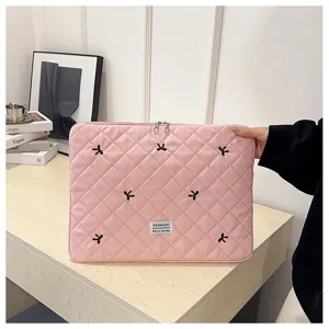 Detalle de funda acolchada rosa para portátil, bonitos lazos negros bordados, suave.