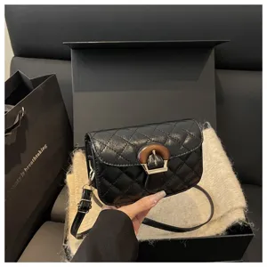 Black quilted shoulder bag detail featuring unique wooden buckle and delicate strap for women.