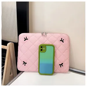 Detalle de funda para laptop acolchada rosa con elegante bordado de lazo negro.