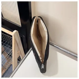 Vista detallada de funda para portátil acolchada negra, bonita bolsa de tablet bordada con cremallera.