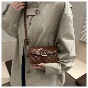 Detail view of brown quilted crossbody bag with wooden buckle and strap, elegant design.