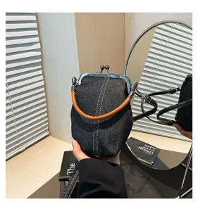 Détail du sac à bandoulière en denim avec fermoir rétro, montrant la texture et le cadre métal.