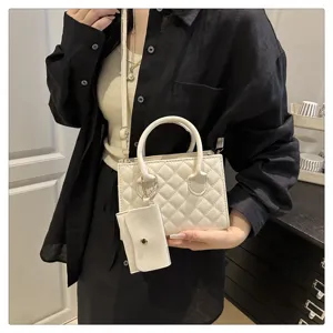 Detail view of stylish white quilted handbag with small pouch and strap, chic design.