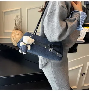 Close-up detail of the sweet denim underarm shoulder bag with contrast belt and bear charm.