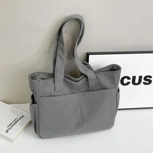 Detail view of grey corduroy tote bag, large shoulder bag with front pocket design.