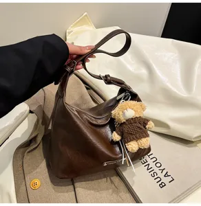 Stylish brown slouchy hobo shoulder bag for women, trendy autumn handbag with cute bear charm.
