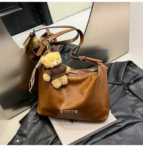 Brown leather shoulder bag detail, stylish hobo purse with cute bear pendant for women.