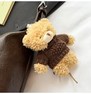 Brown leather underarm shoulder bag featuring a cute fluffy teddy bear plush pendant charm.