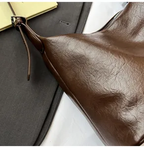 Close-up detail of dark brown leather hobo underarm bag showing soft texture and adjustable strap.