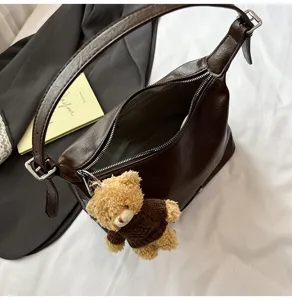 Detailed view of the dark brown leather hobo shoulder bag with a cute plush bear pendant.
