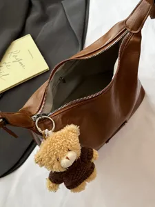 Brown PU leather shoulder bag for women, stylish underarm crossbody bag with cute teddy bear pendant.
