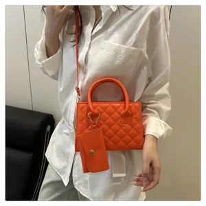 Detailed view of orange quilted crossbody bag with small pouch, stylish design, premium texture.