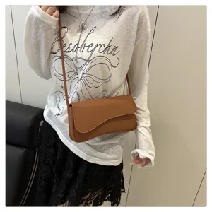 Detail view of stylish brown leather underarm shoulder bag with unique curved flap design.