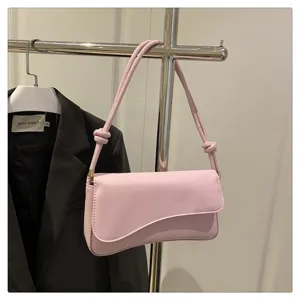 Chic pink French baguette shoulder bag featuring a curved flap and stylish knot strap.