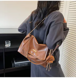 Gedetailleerd overzicht van de vintage bruine schoudertas met kettingriem en leuke hanger.