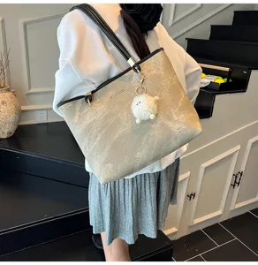 Gedetailleerd overzicht van grote shopper tas met pluizige hanger op de schouder.
