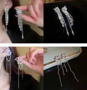 Primo piano di orecchini con nappe floreali in strass scintillanti e dettagli di clip.
