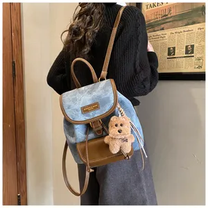 Detailaufnahme des Retro-Denim-Rucksacks mit Plüschbären-Anhänger für den Weg zur Arbeit.