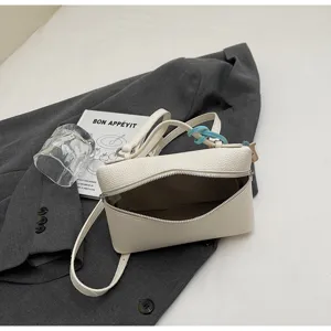Detalle de bolso cruzado de cuero texturizado blanco, bolso casual elegante con cierre de cremallera.