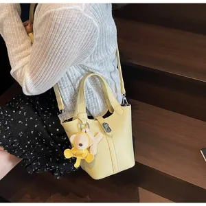 Vista detallada del bolso tipo cubo de cuero amarillo, bolso casual con bonito colgante.