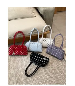 Detailed view of trendy polka dot shoulder pillow bags with star charms, displayed on carpet.