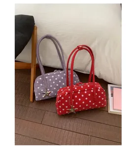 Detail view of stylish polka dot shoulder bags in purple and red, featuring charming star pendants.
