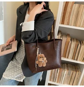 Elegante bolso marrón con colgante de oso de peluche, bolso grande de hombro de cuero PU.