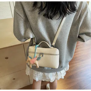 Primer plano del bolso bandolera beige texturizado con cremallera y bonito colgante.